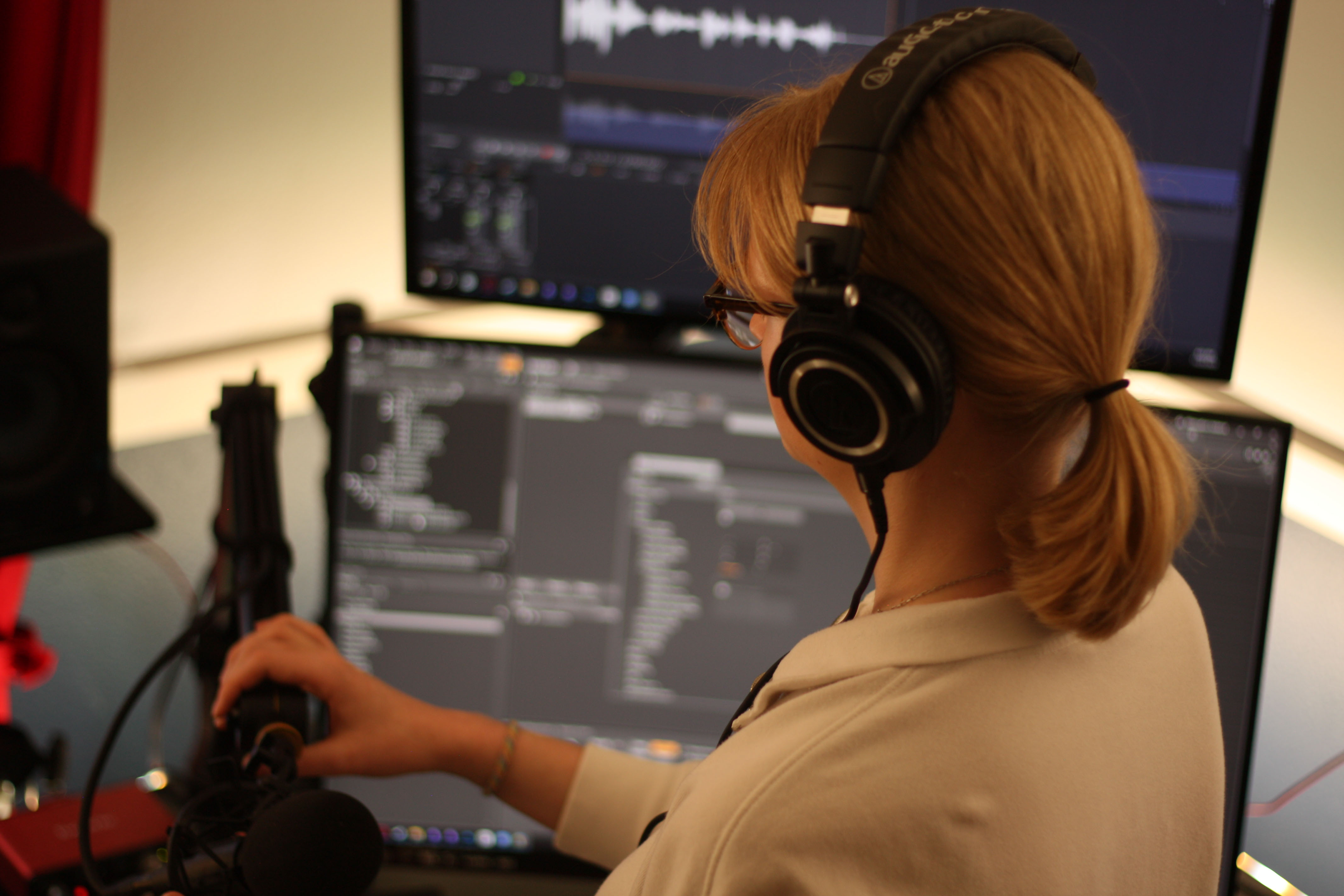 Emelie Kronquist with a microphone and computer screens.